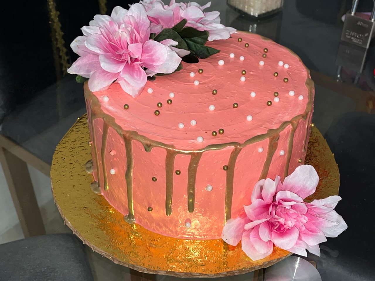 Bizcocho rosado con drip dorado y flores